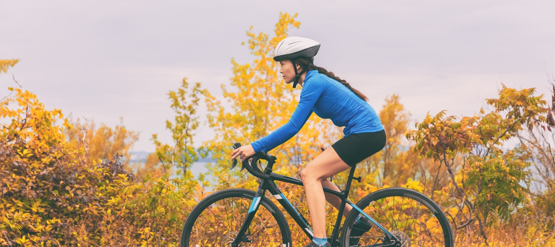 A woman in blue shirt and shorts biking on a beautiful autumn day