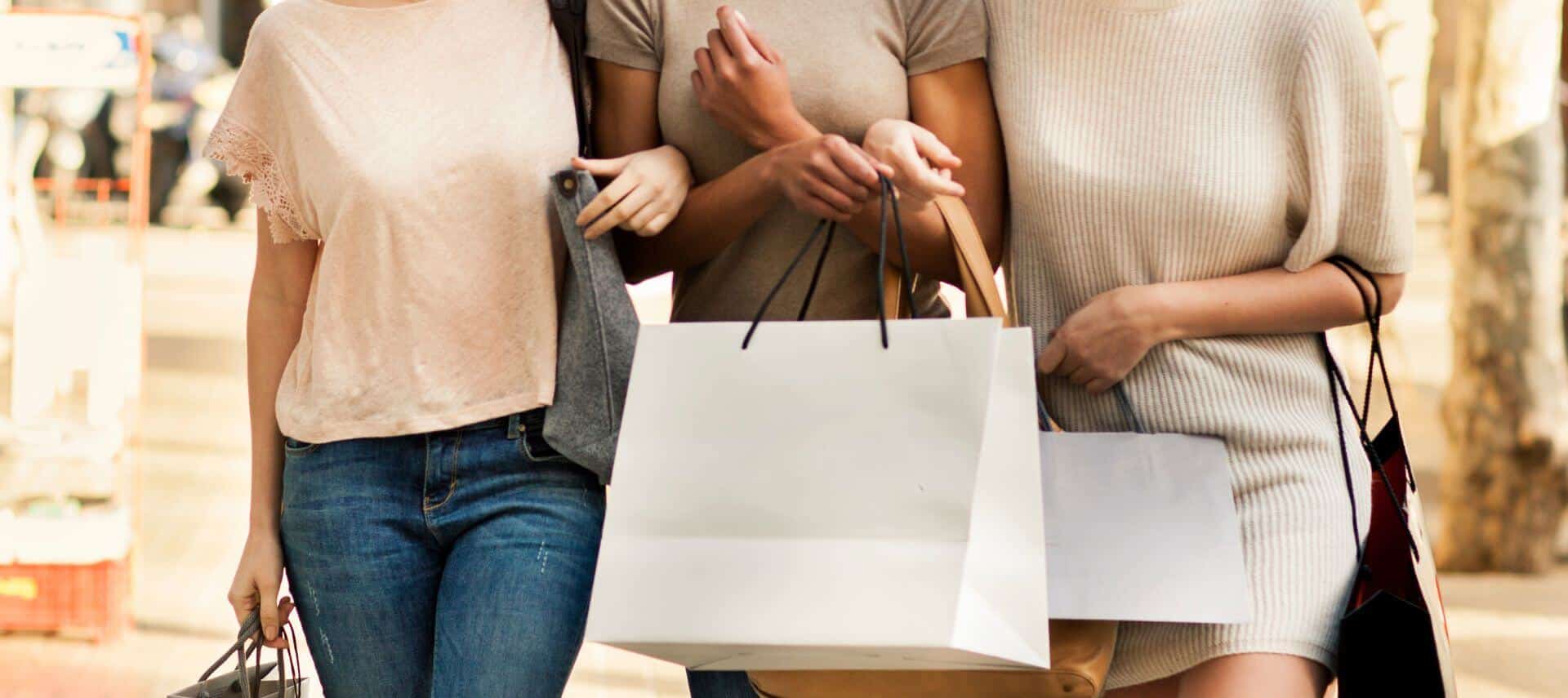 Three women in a shopping plaza holding shopping bags